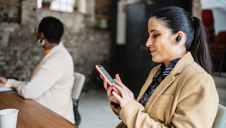 businesswoman using smartphone and earphones during meeting